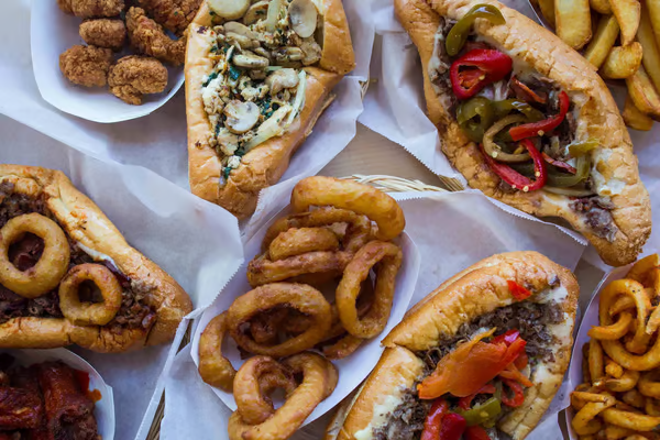 There are many different types of sandwiches and french fries on the table.