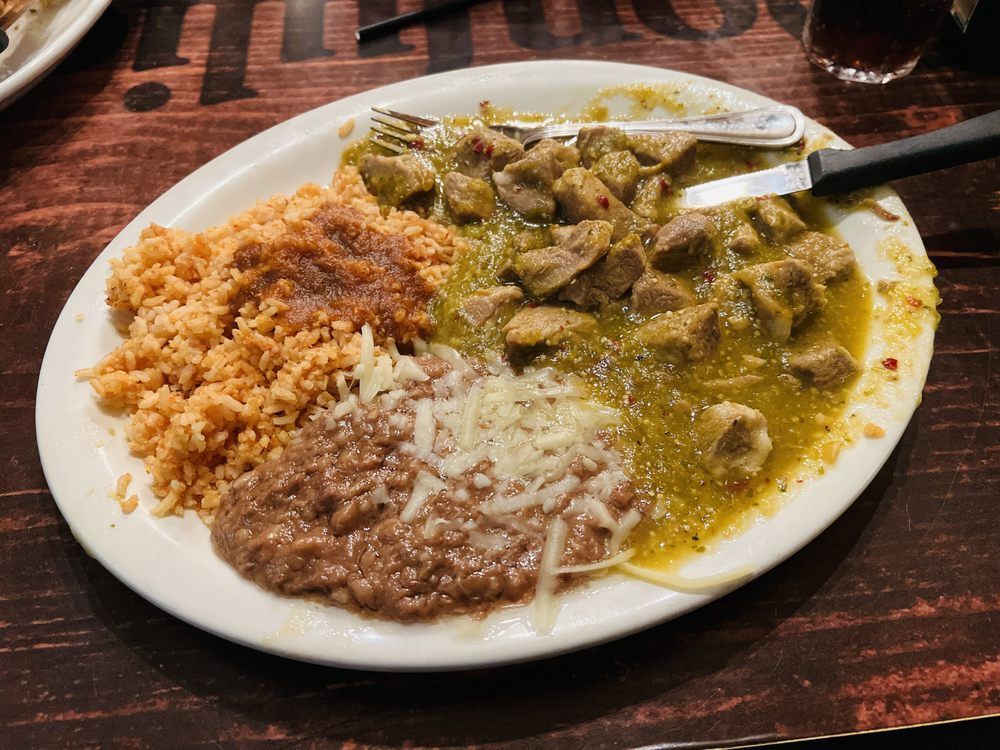 A plate of food with rice beans and meat on a table.