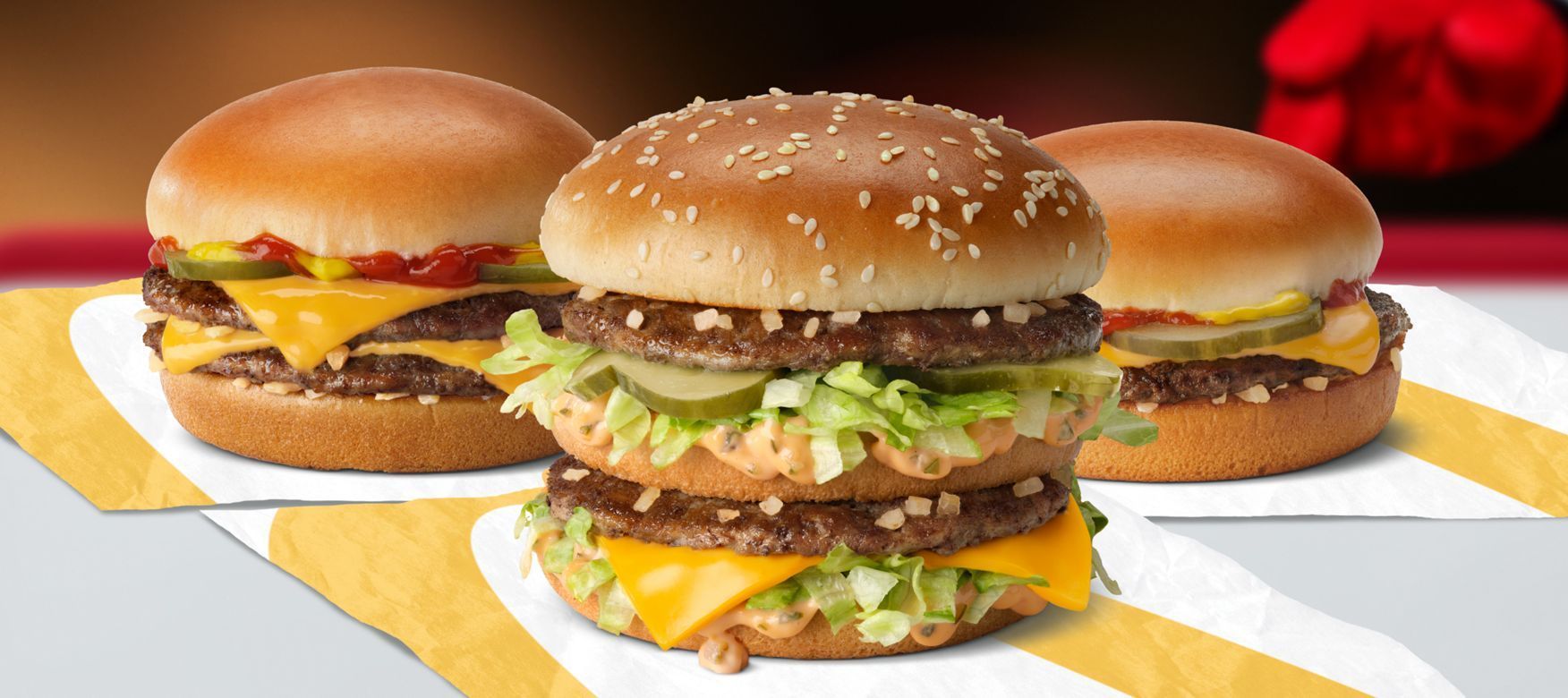 Three hamburgers are sitting on a napkin on a table.