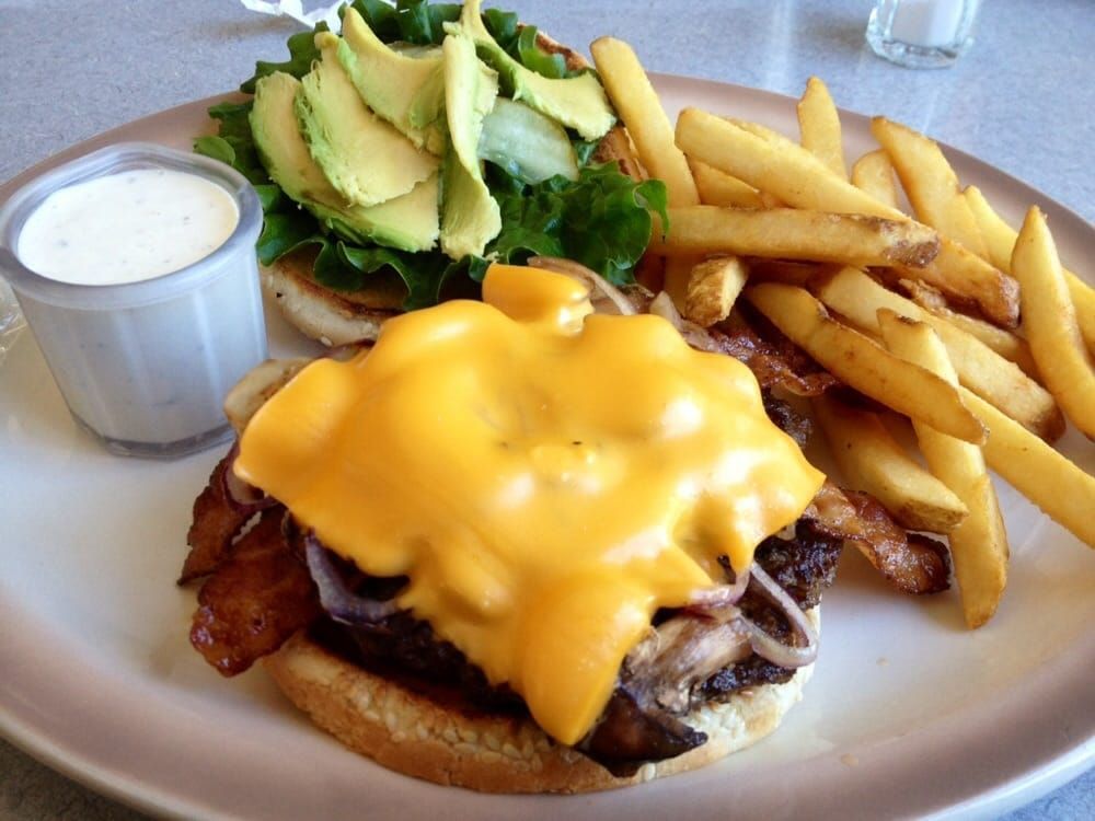 A cheeseburger with bacon and french fries on a plate