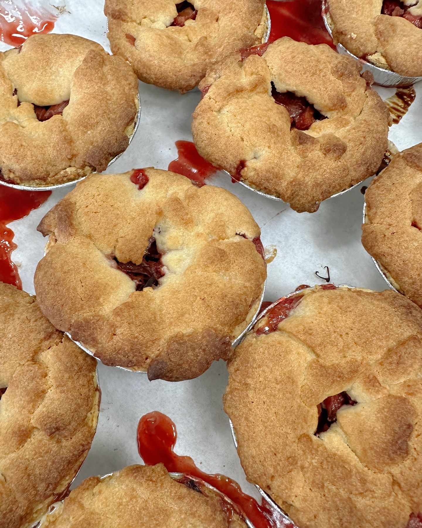 A bunch of pies are sitting on a table with ketchup on them