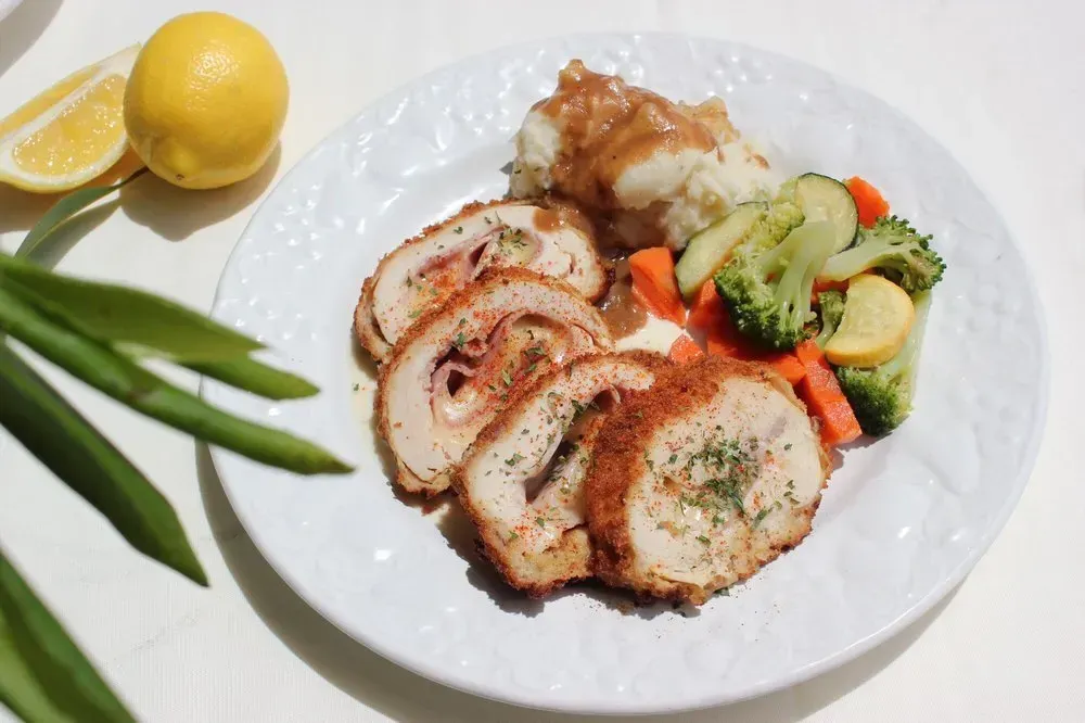 A white plate topped with meat and vegetables on a table.