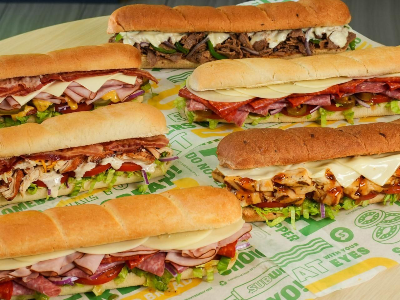 A variety of sub sandwiches are sitting on a table.