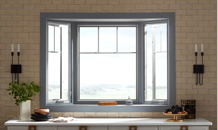 Bay window with grey trim, open side windows, overlooking a landscape. White countertop, sconces.
