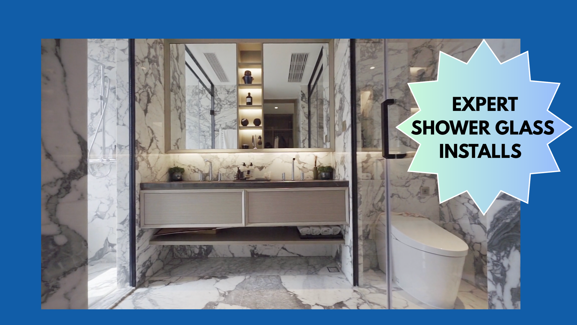 Bathroom with marble walls, glass shower, and vanity. 