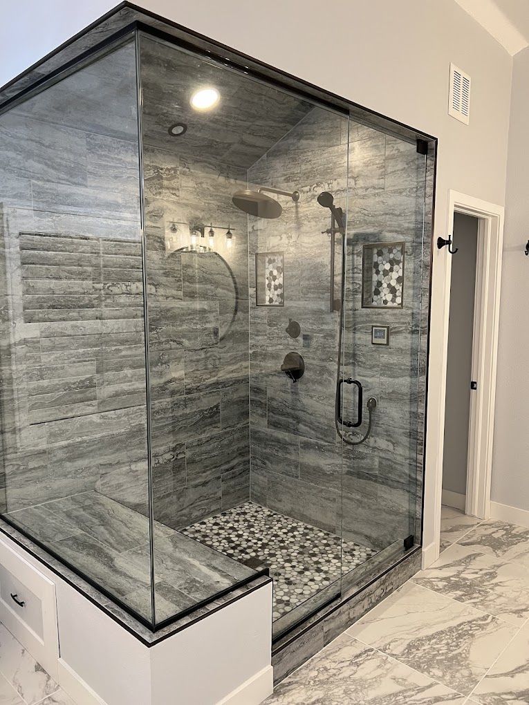 A bathroom with a walk in shower with a glass door.