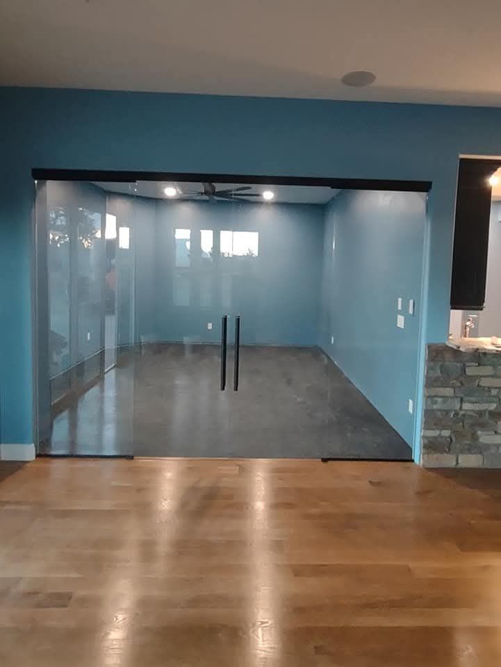 Glass sliding doors leading into a room with blue walls and hardwood floors.
