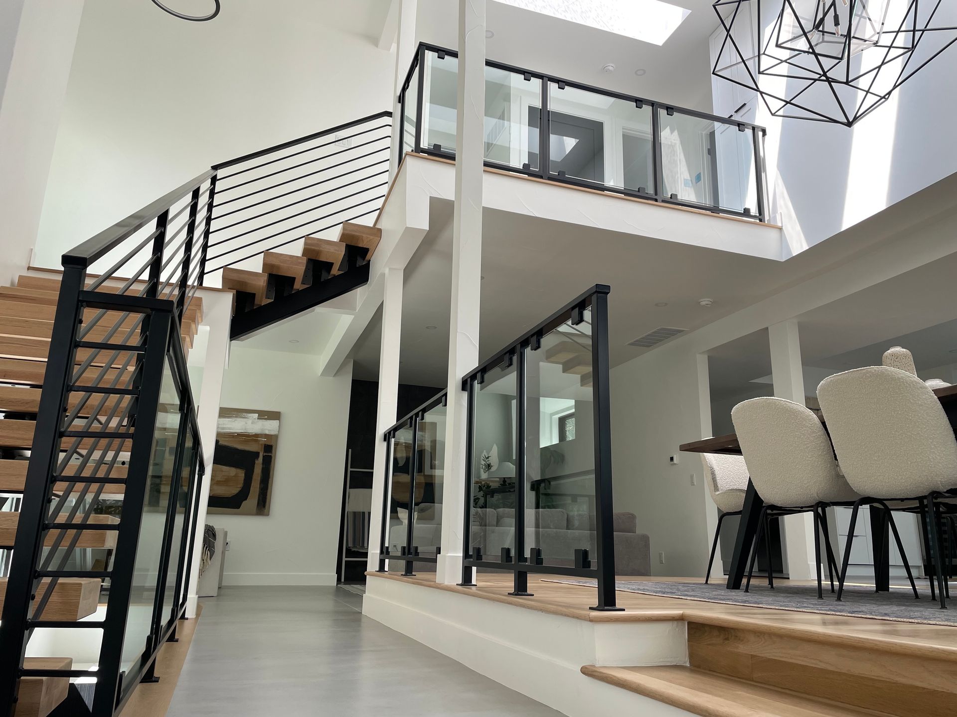 Modern two-story home interior with a staircase and glass railings. Wooden steps and white walls.