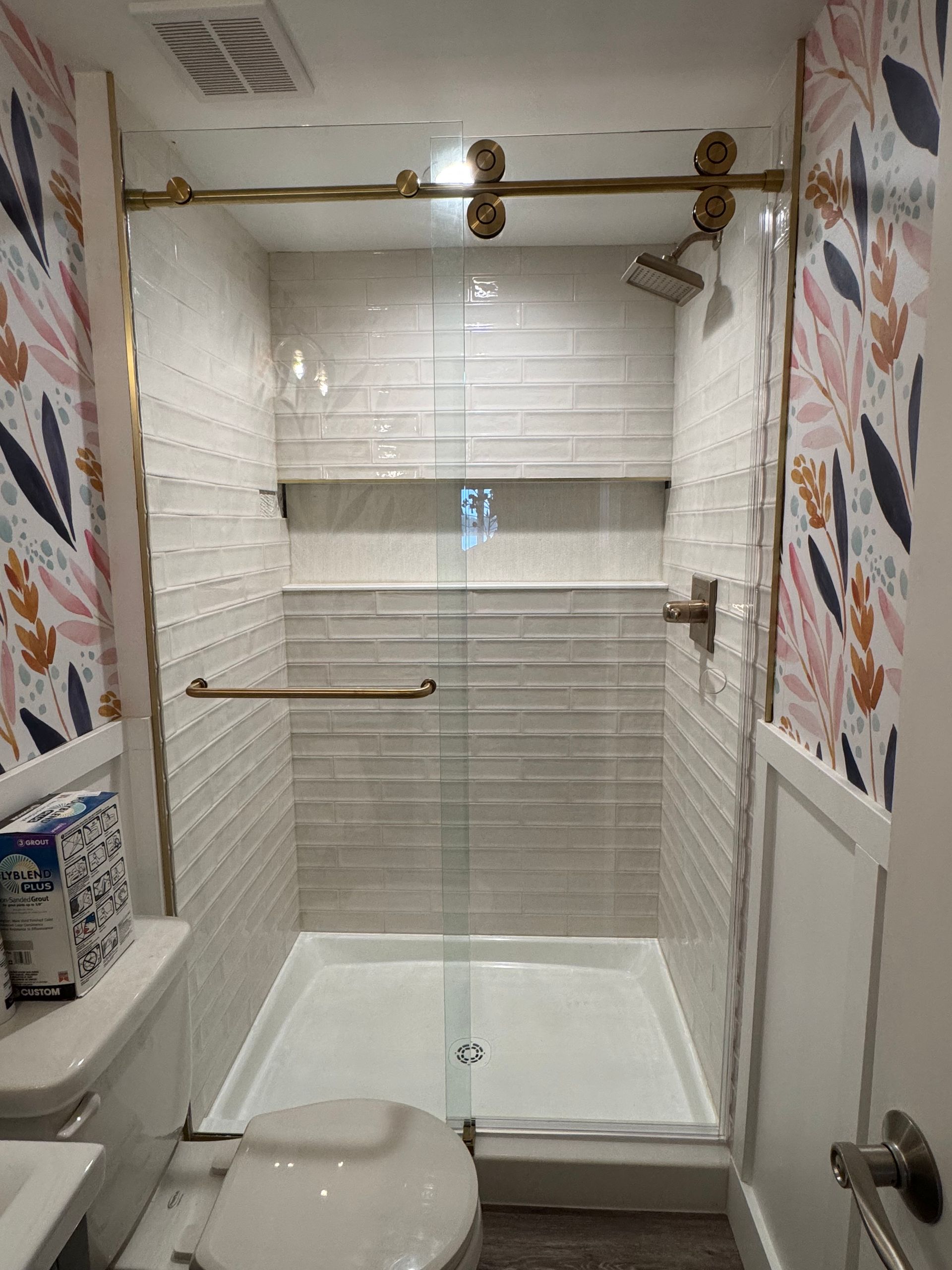 A bathroom with a toilet , sink , shower and sliding glass door.