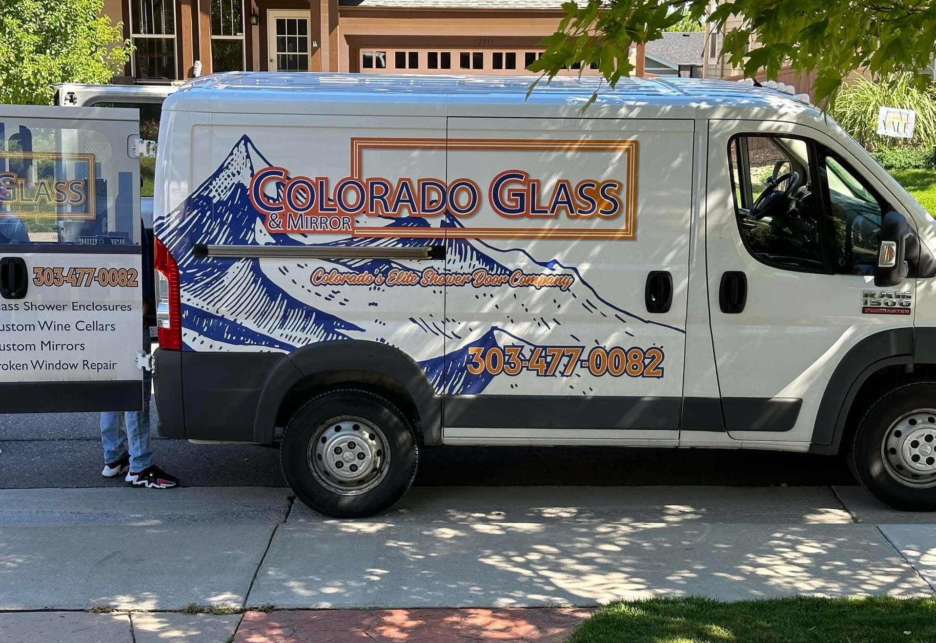 White Colorado Glass repair van parked on a street; person by the open door.