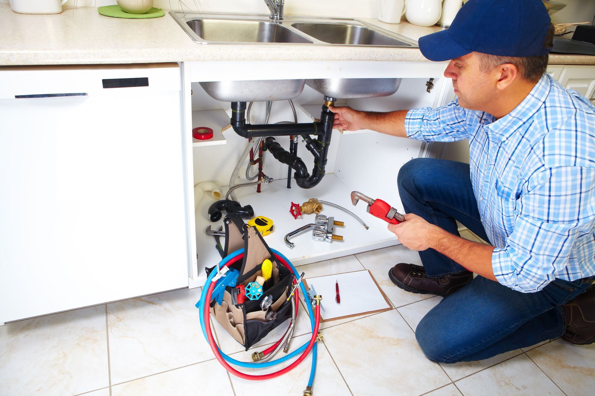 A plumber is fixing a sink in a kitchen.