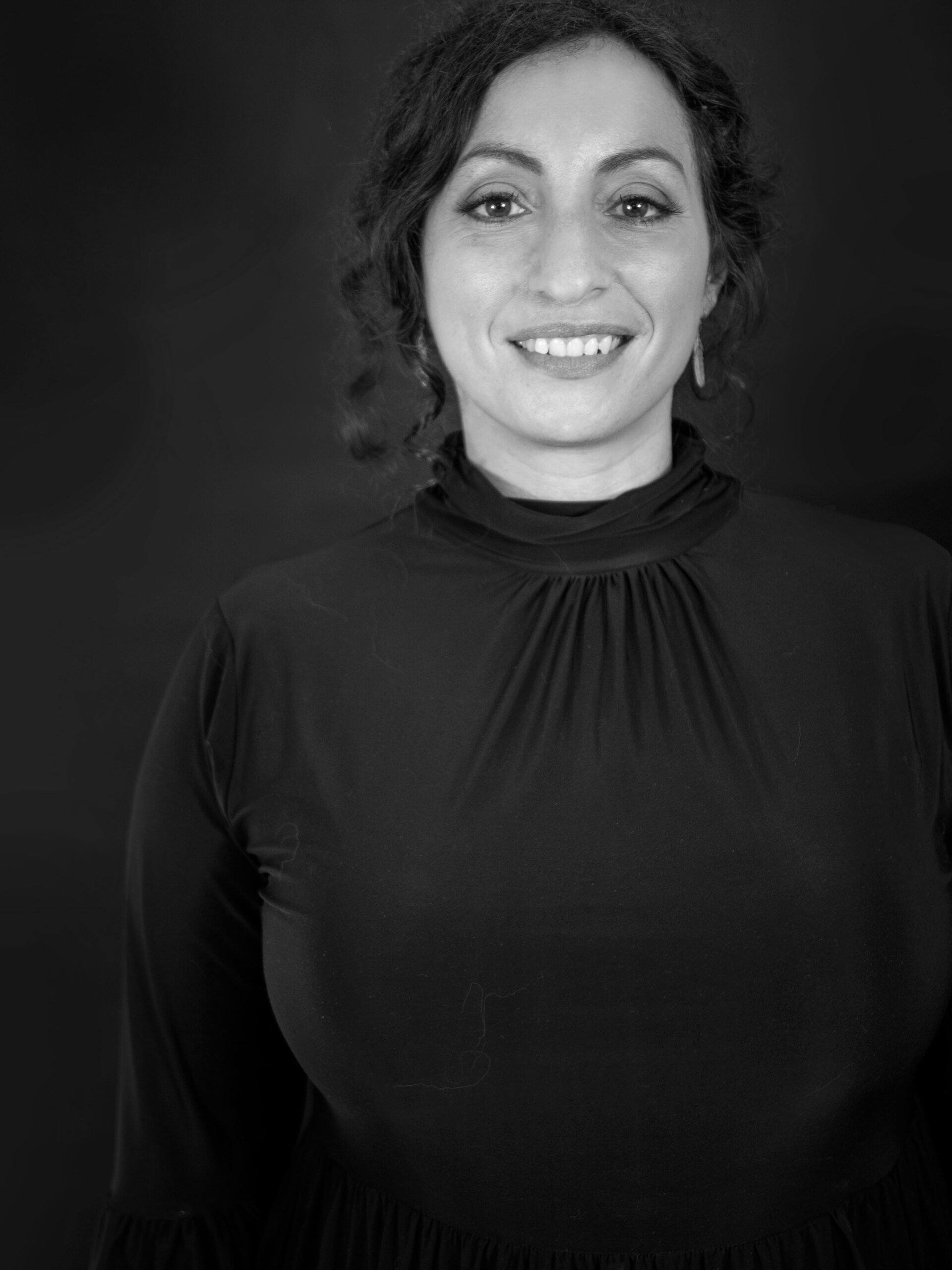 A woman in a black shirt is smiling in a black and white photo.