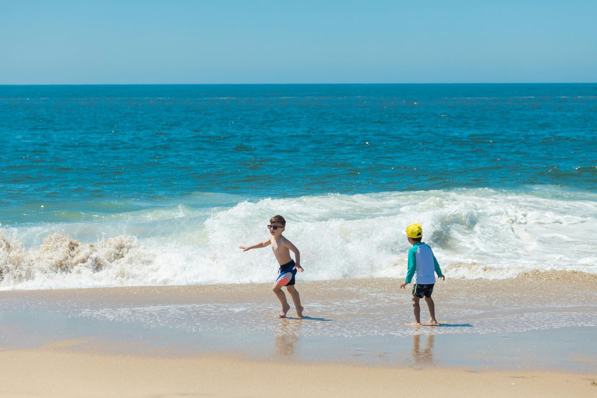 Two young boys are playing in the water on the beach.