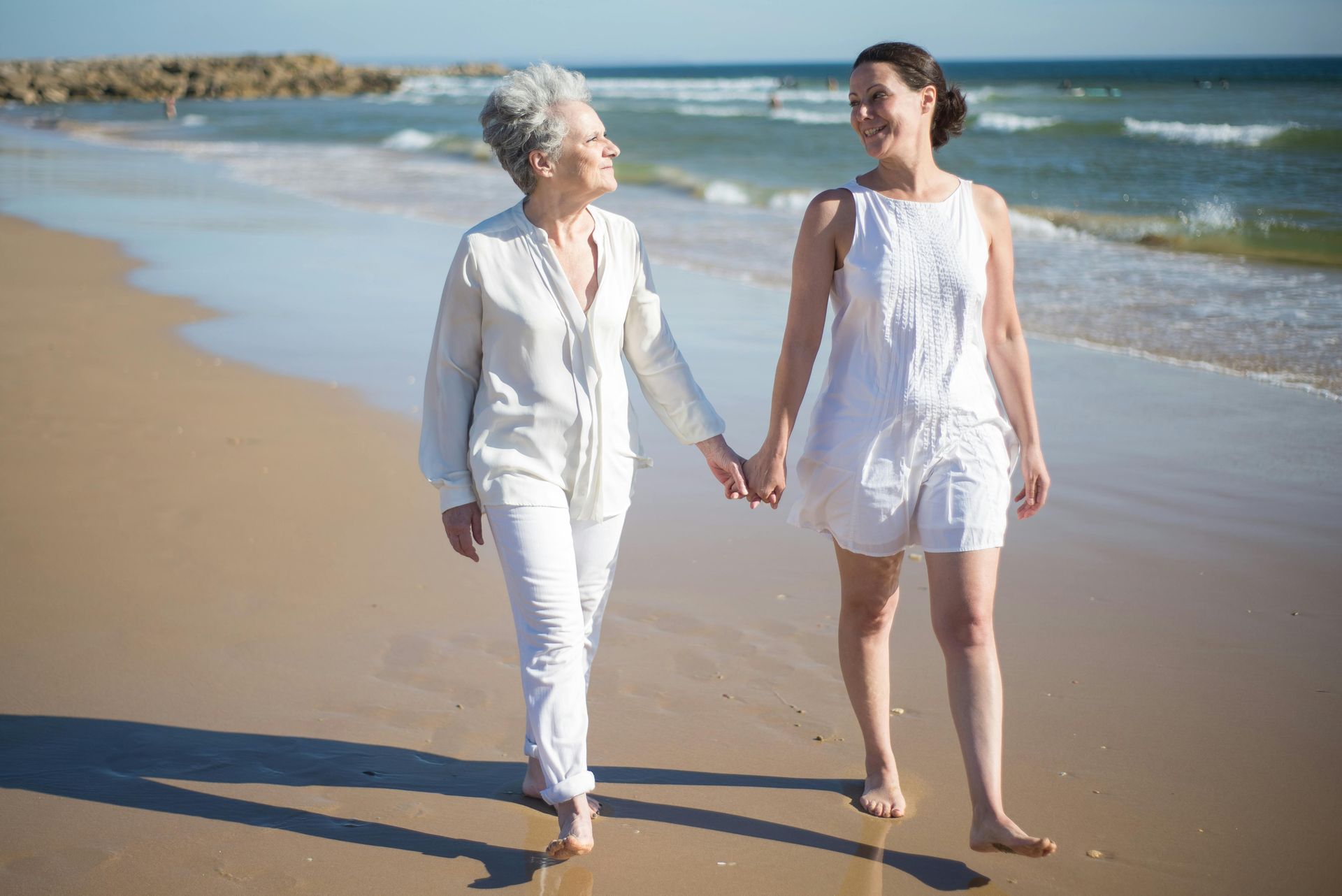 Woman comforts elderly woman outdoors, hand on shoulder.