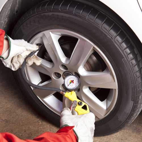 Mechanic checking the air pressure of a car wheel