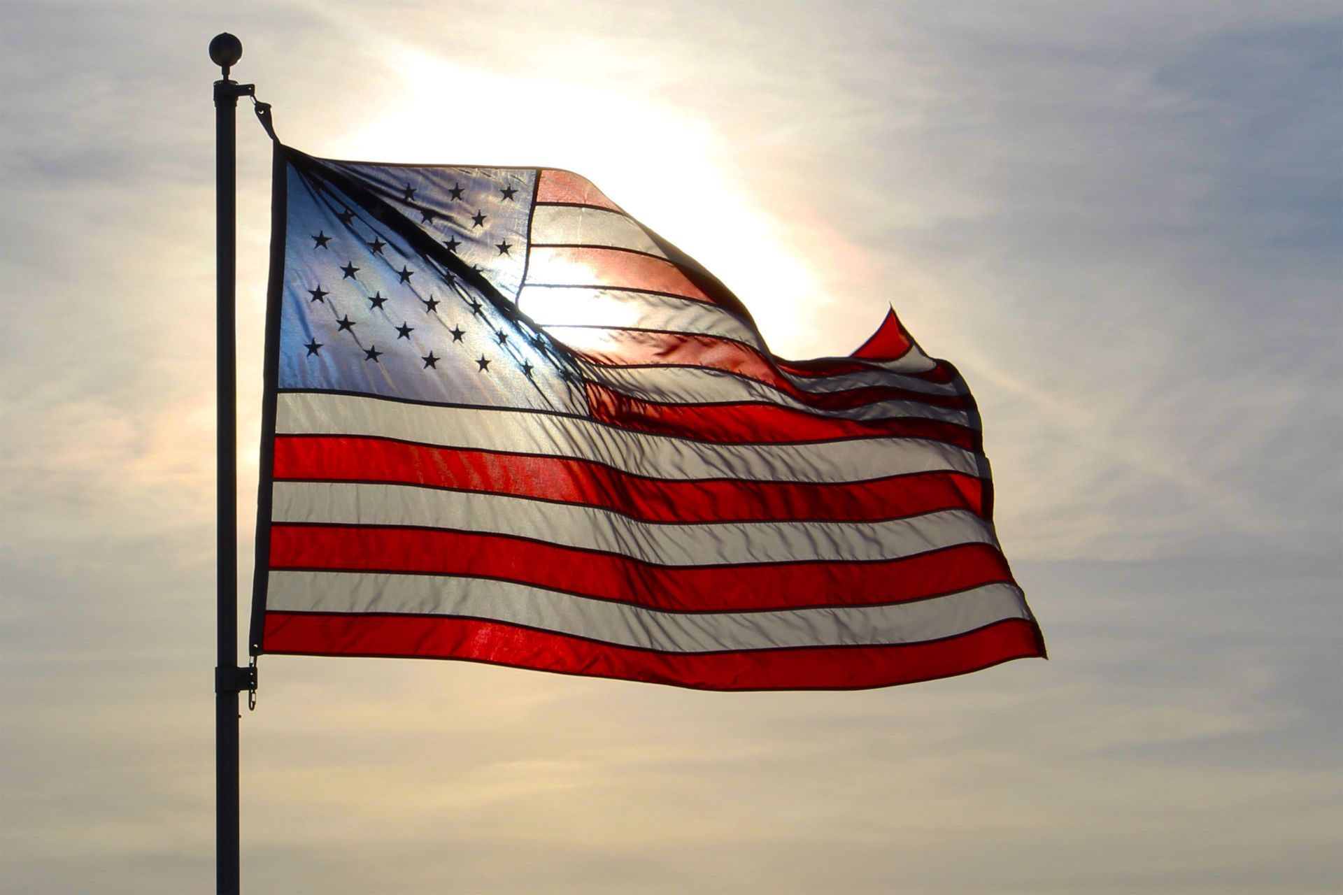 American flag waving on a pole against a sunset sky