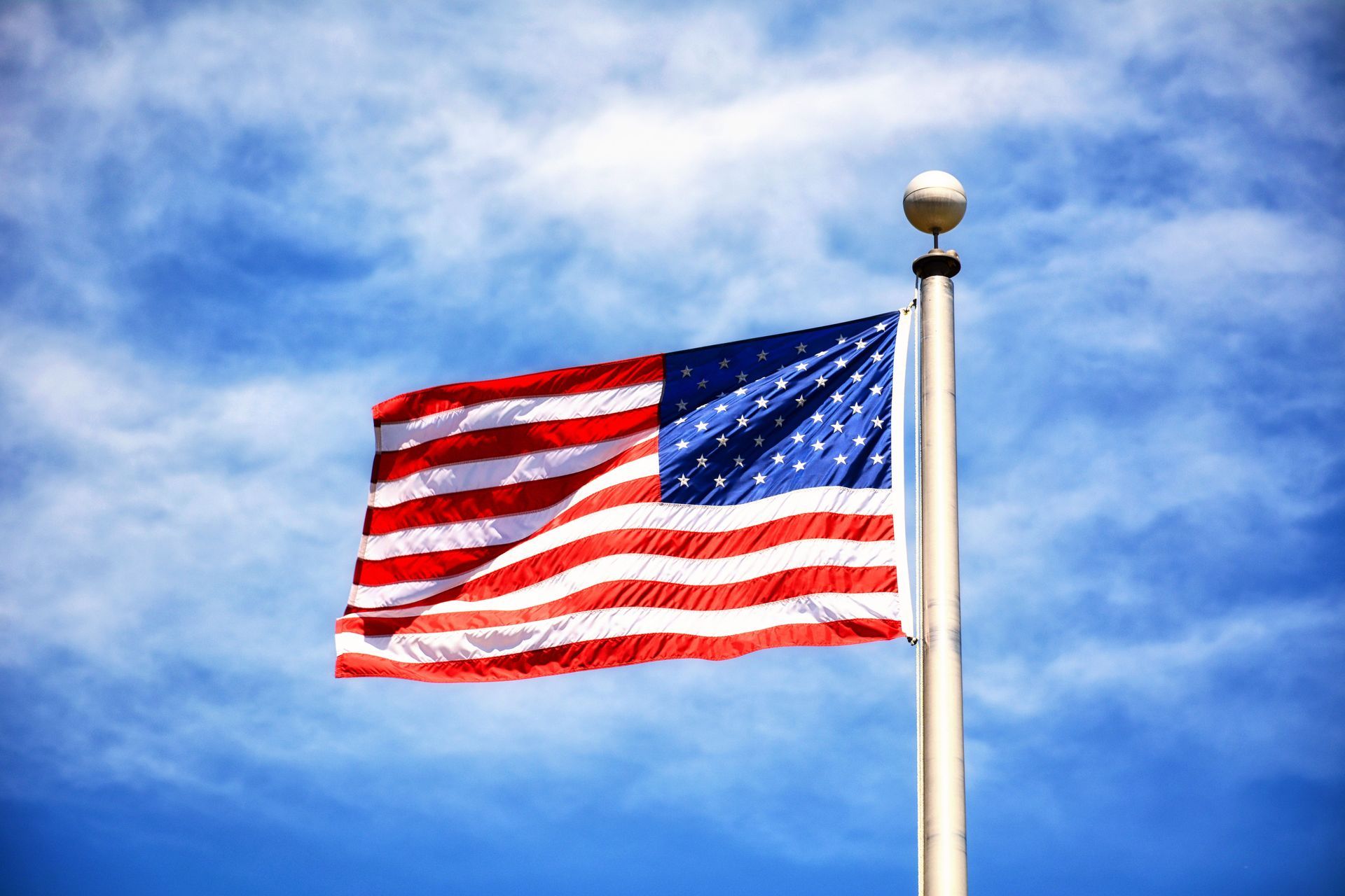 American flag waving on a flagpole against a blue sky
