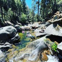 A lake near by the Italian Bar Cabin surrounded by granite rocks and tall trees.