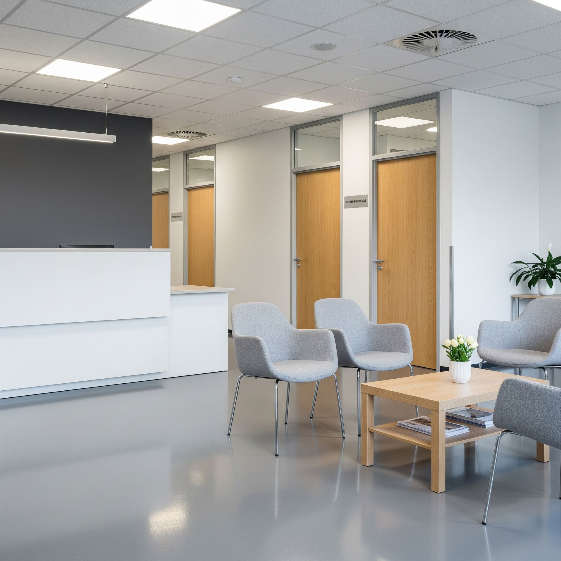 A modern waiting room with gray chairs, a wooden coffee table, and light-colored doors. The floors are glossy.