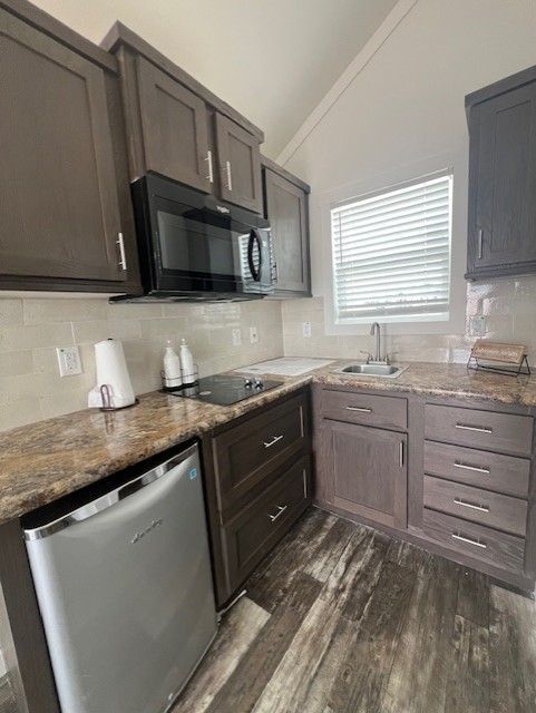 A kitchen with wooden cabinets, granite counter tops, a refrigerator and a microwave.