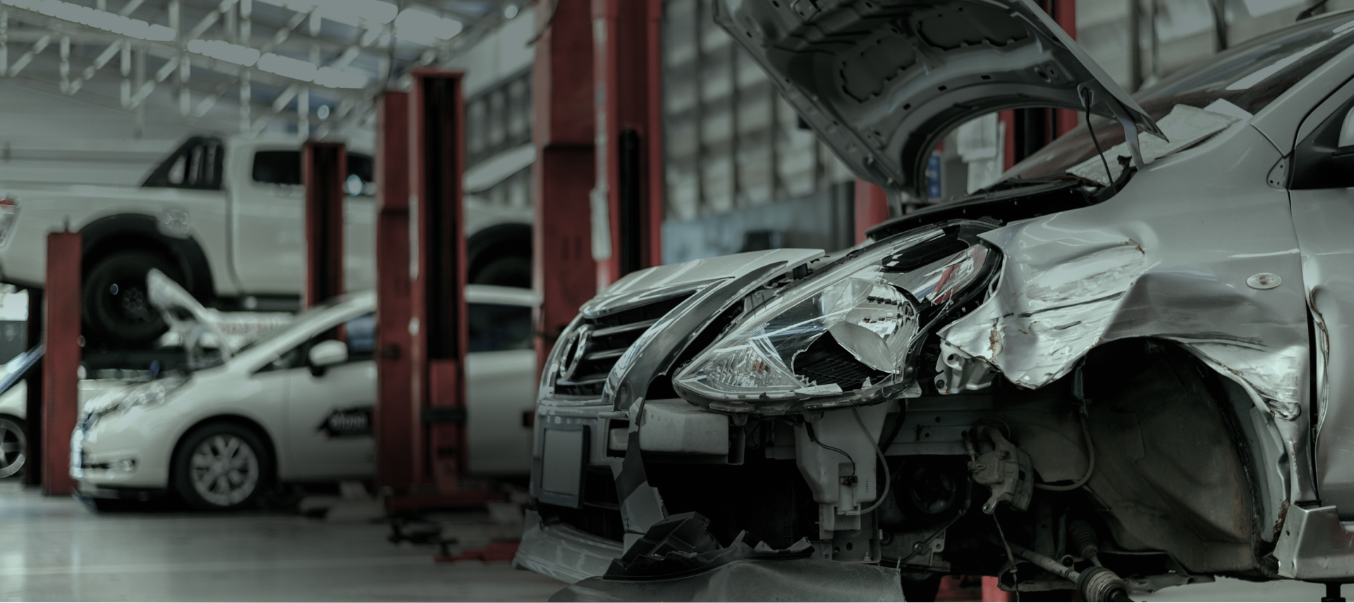 A row of cars are sitting on lifts in a garage. | Morrison Corp Mobile Body & Paint