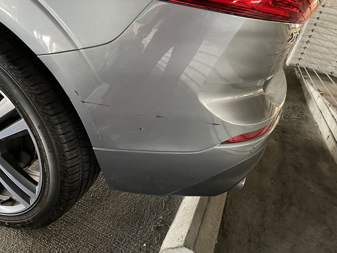 A silver car with a damaged bumper is parked in a parking lot. | Morrison Corp Mobile Body & Paint