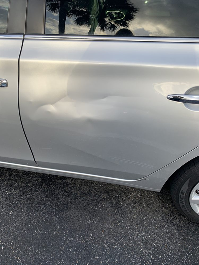 A silver car with a damaged door is parked on the side of the road. | Morrison Corp Mobile Body & Paint