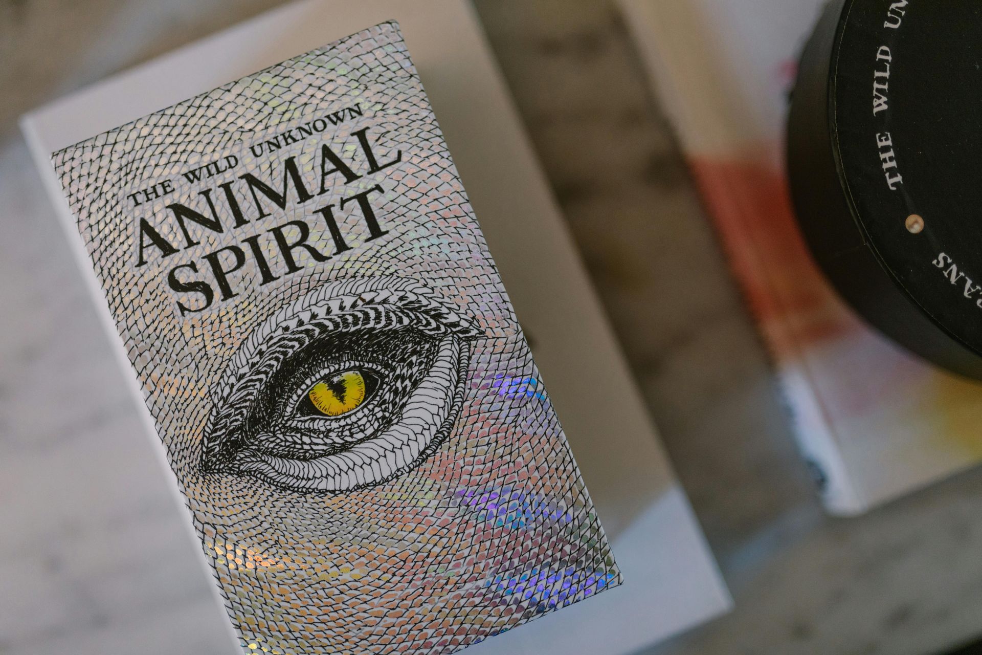 A book called animal spirit is sitting on a table next to a camera lens.