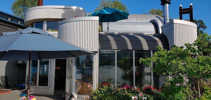 A large white house with a blue umbrella in front of it.