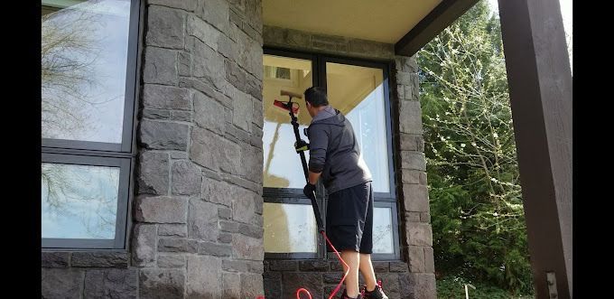 Professional window cleaner using advanced tools to clean residential windows in Portland, Oregon.