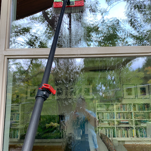 Professional window cleaner using a water-fed pole for spotless window cleaning services in Portland.