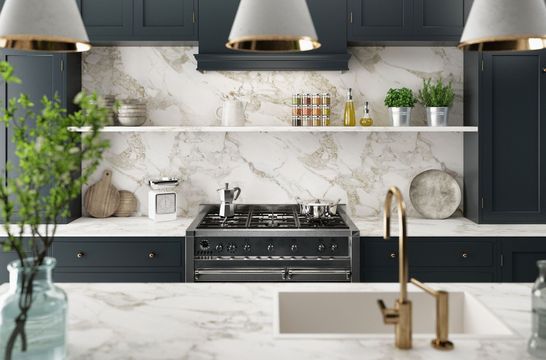 Modern kitchen with dark navy cabinets, white marble countertops, a gas stove, and hanging pendant lights.