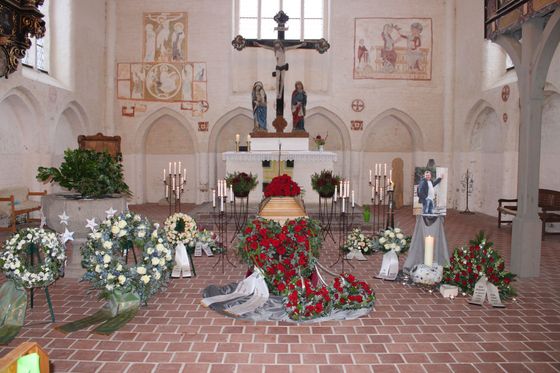 Bestatter Stralsund: in einer Kirche steht ein Sarg mit Blumen und Kerzen