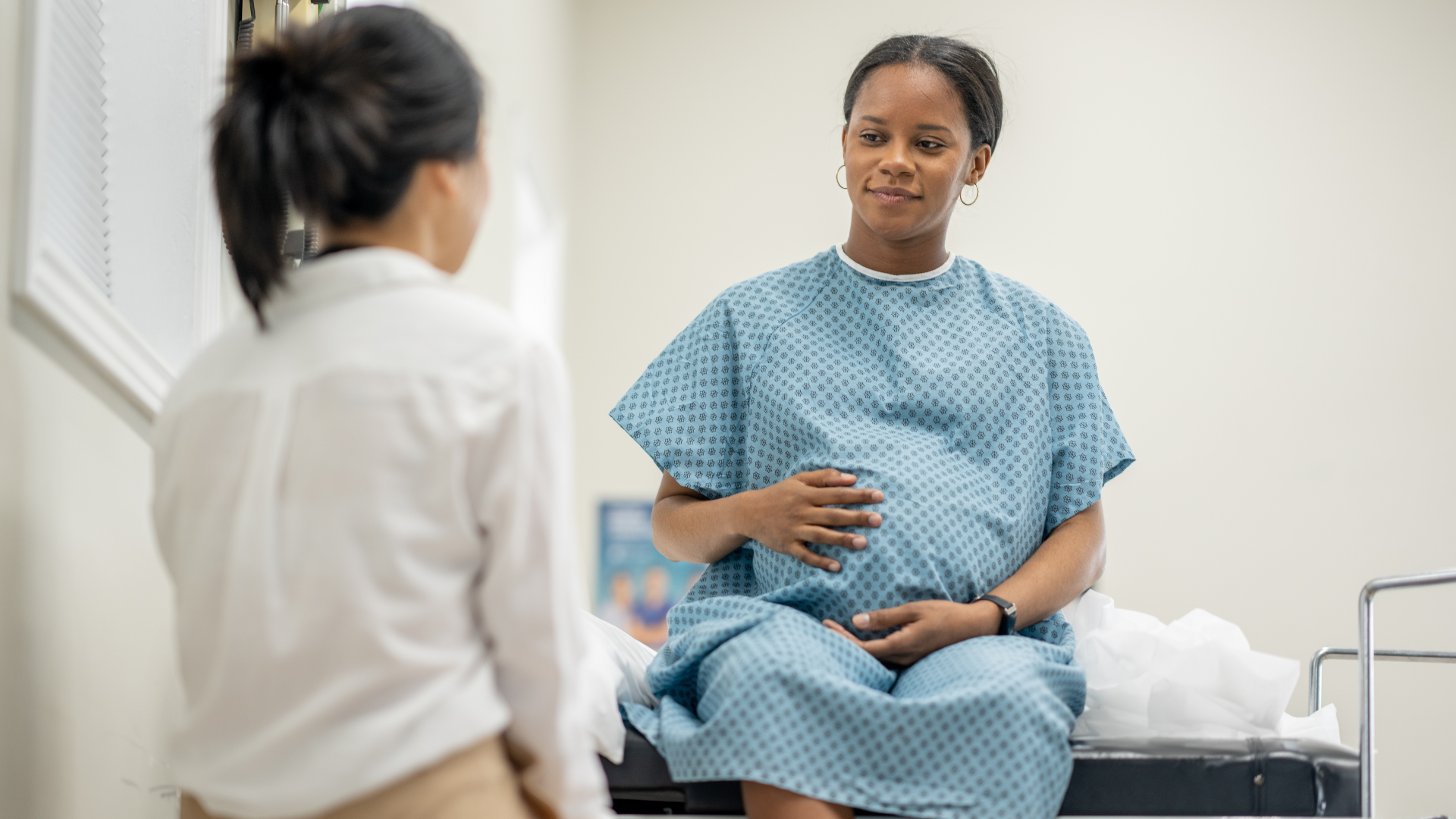 A pregnant woman is laying in a hospital bed holding her belly.