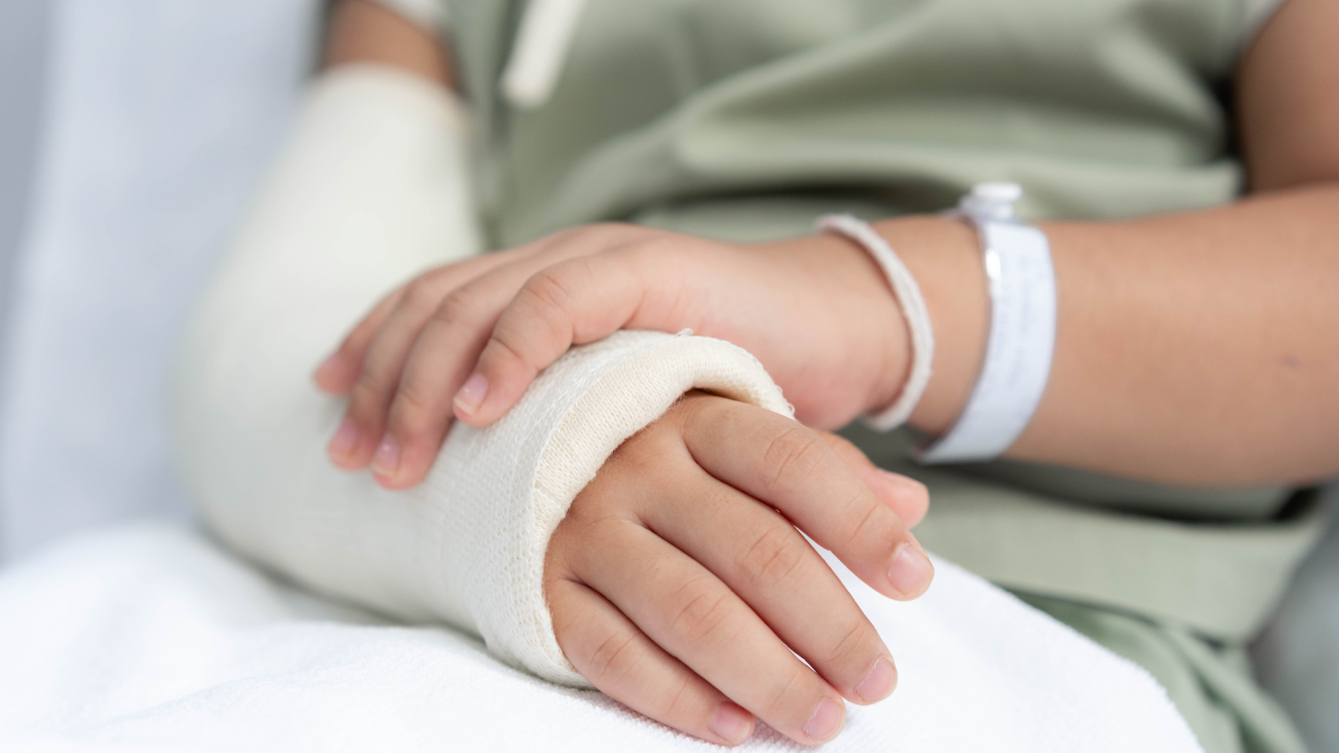 A person with a cast on their arm is sitting in a hospital bed.