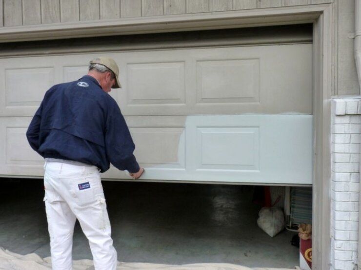 A man painting the garage door white — Killeen, TX — Killeen Overhead Doors