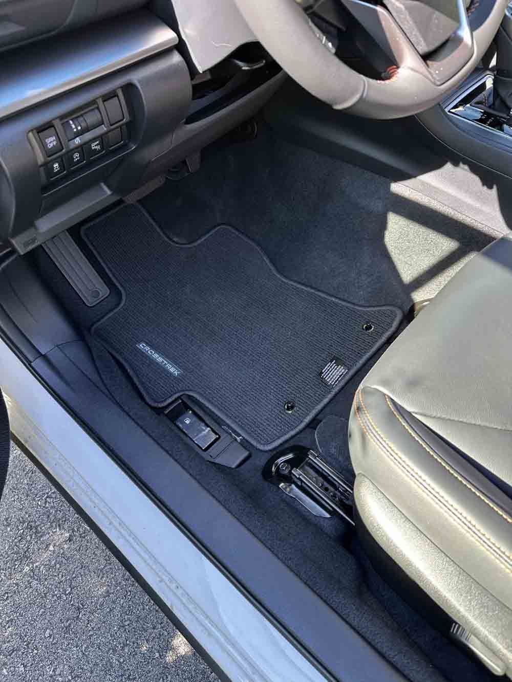 the interior of a white subaru outback with a black floor mat .