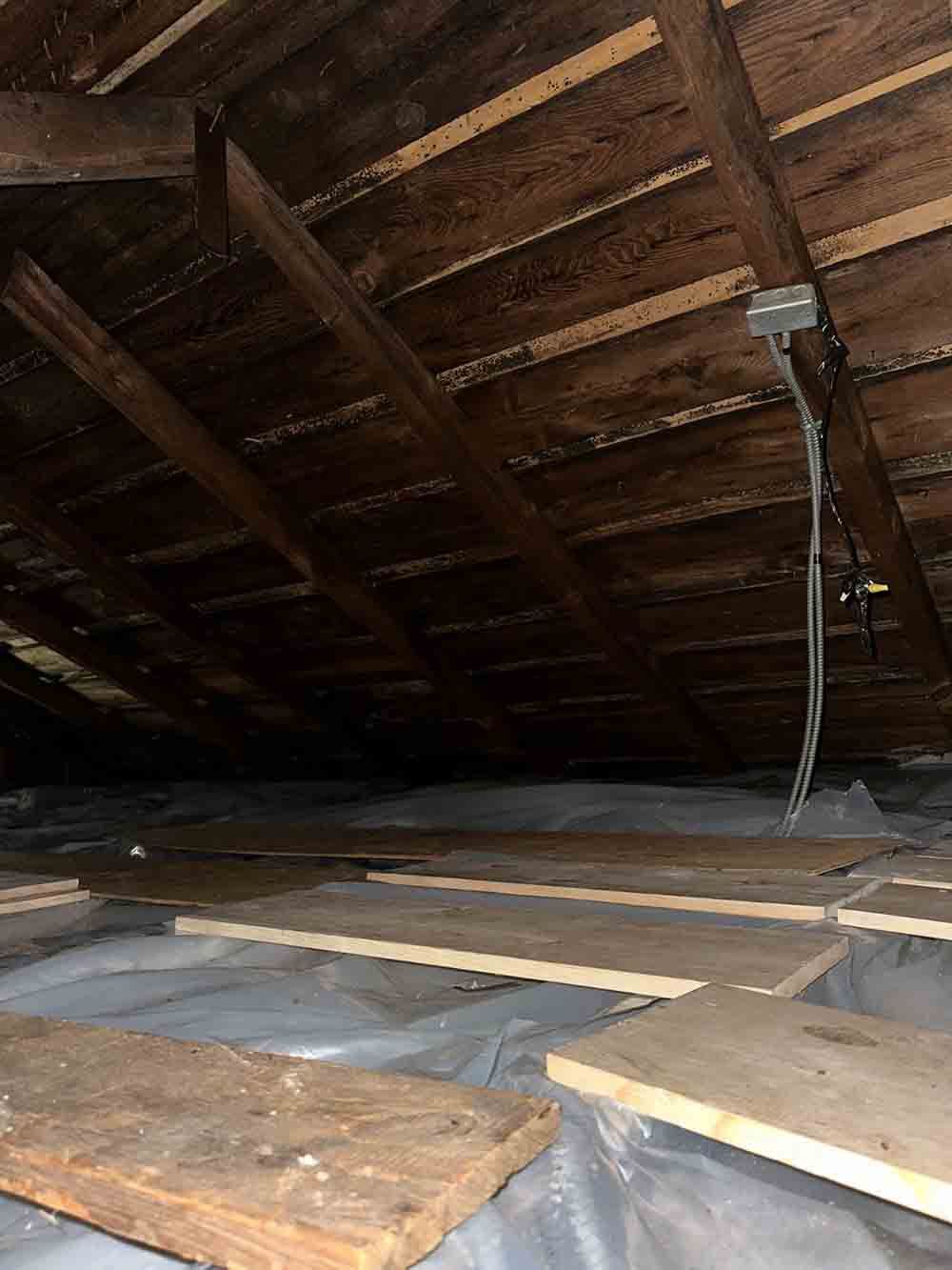 the ceiling of an attic is covered in plastic and wooden beams .
