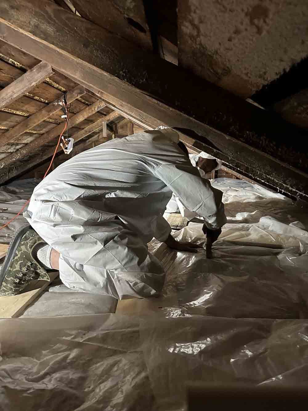 a man in a protective suit is working under a wooden ceiling
