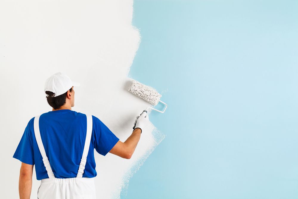 a man is painting a wall with a paint roller .