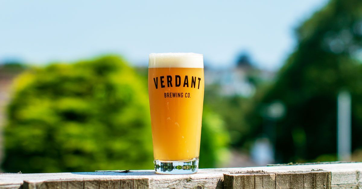 A glass of beer is sitting on a wooden table.