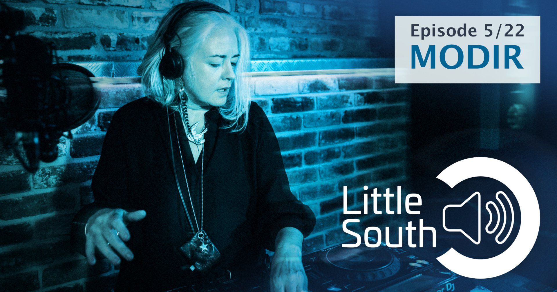 A woman wearing headphones is standing in front of a brick wall with the words little south on the bottom