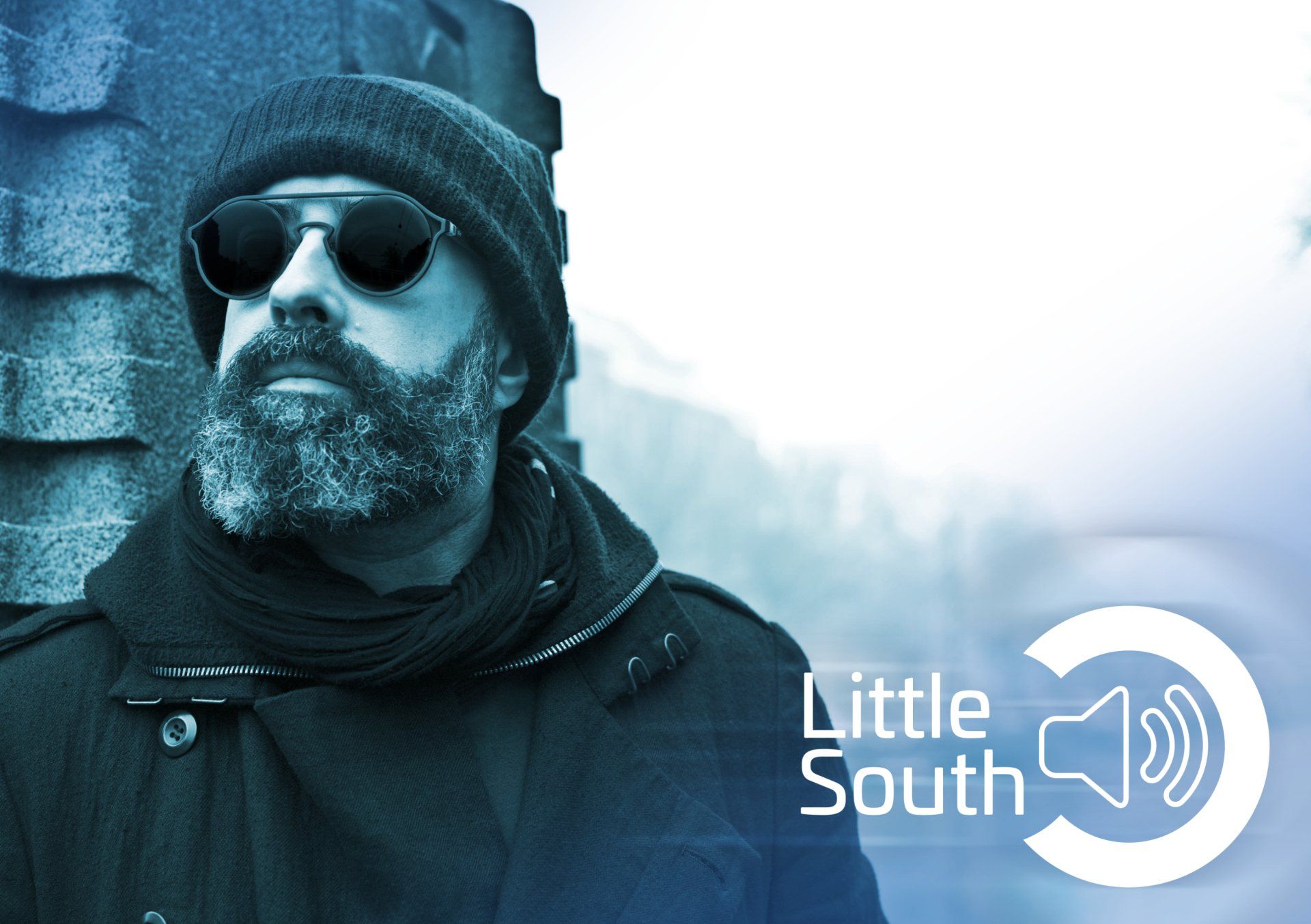 A man with a beard wearing sunglasses and a little south logo