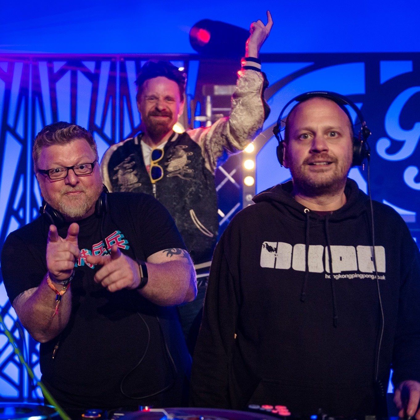 Three men are standing in front of a sign that says ' g ' on it