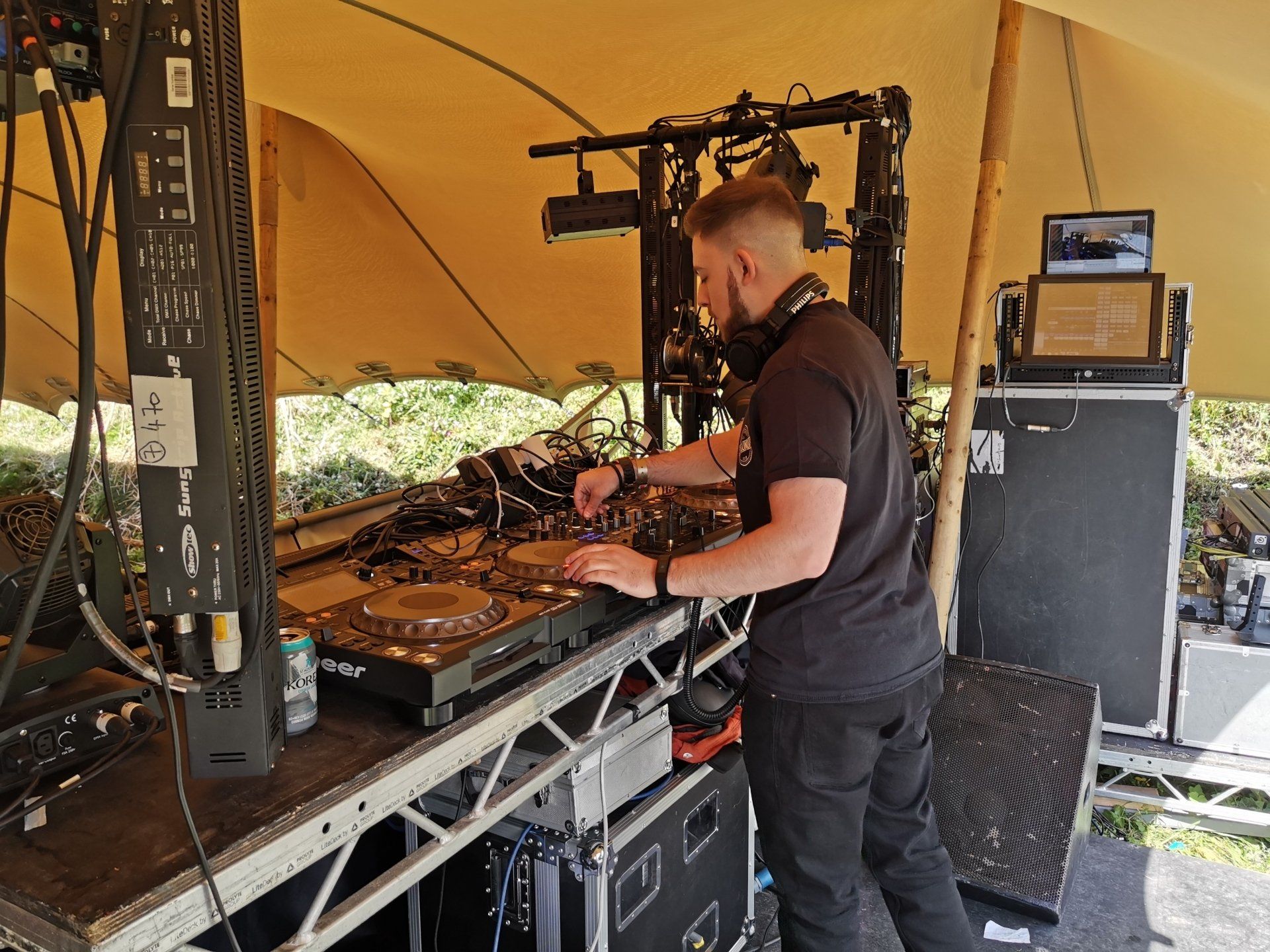 A man in a black shirt is standing in front of a dj booth.