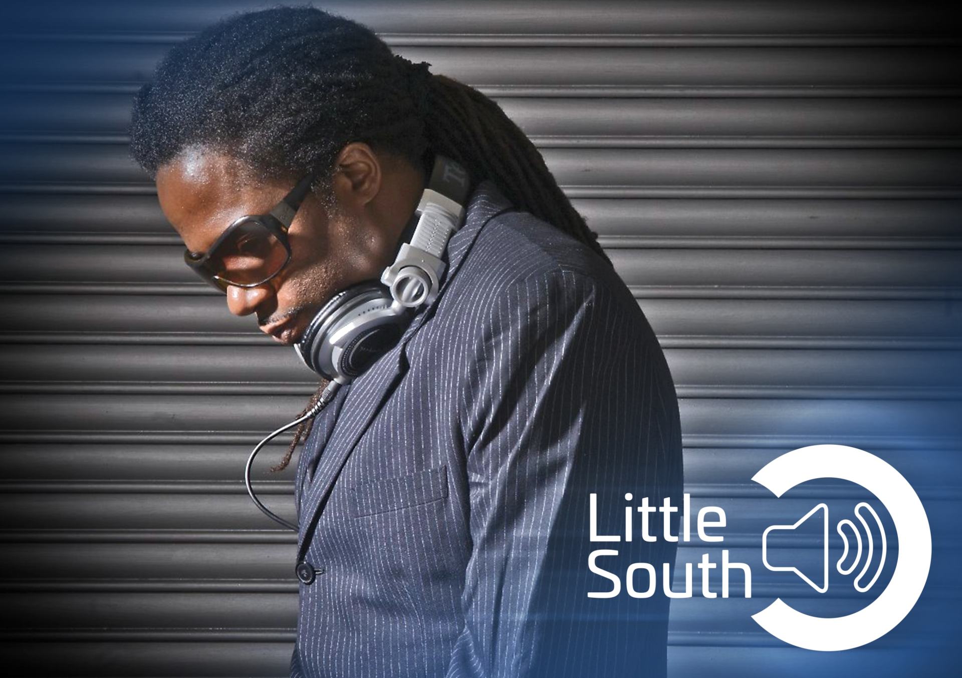 A man wearing headphones is standing in front of a sign that says little south