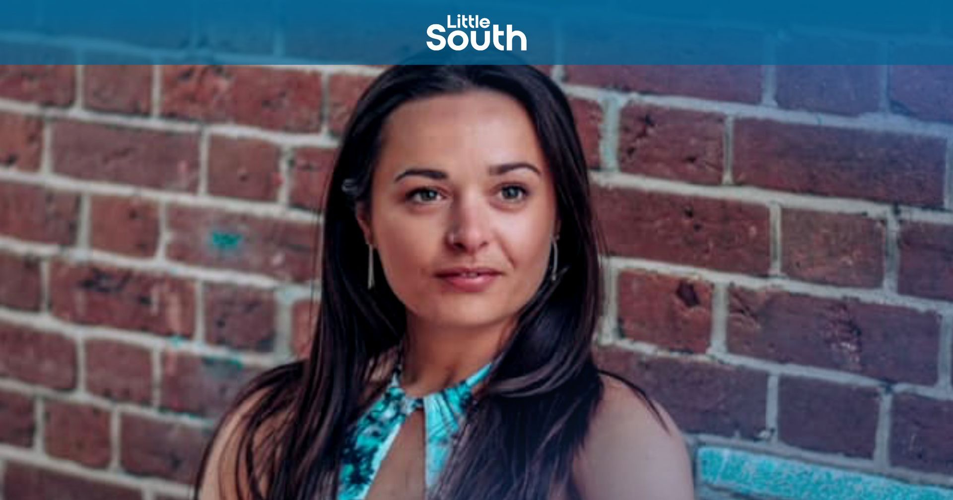 A woman is standing in front of a brick wall.