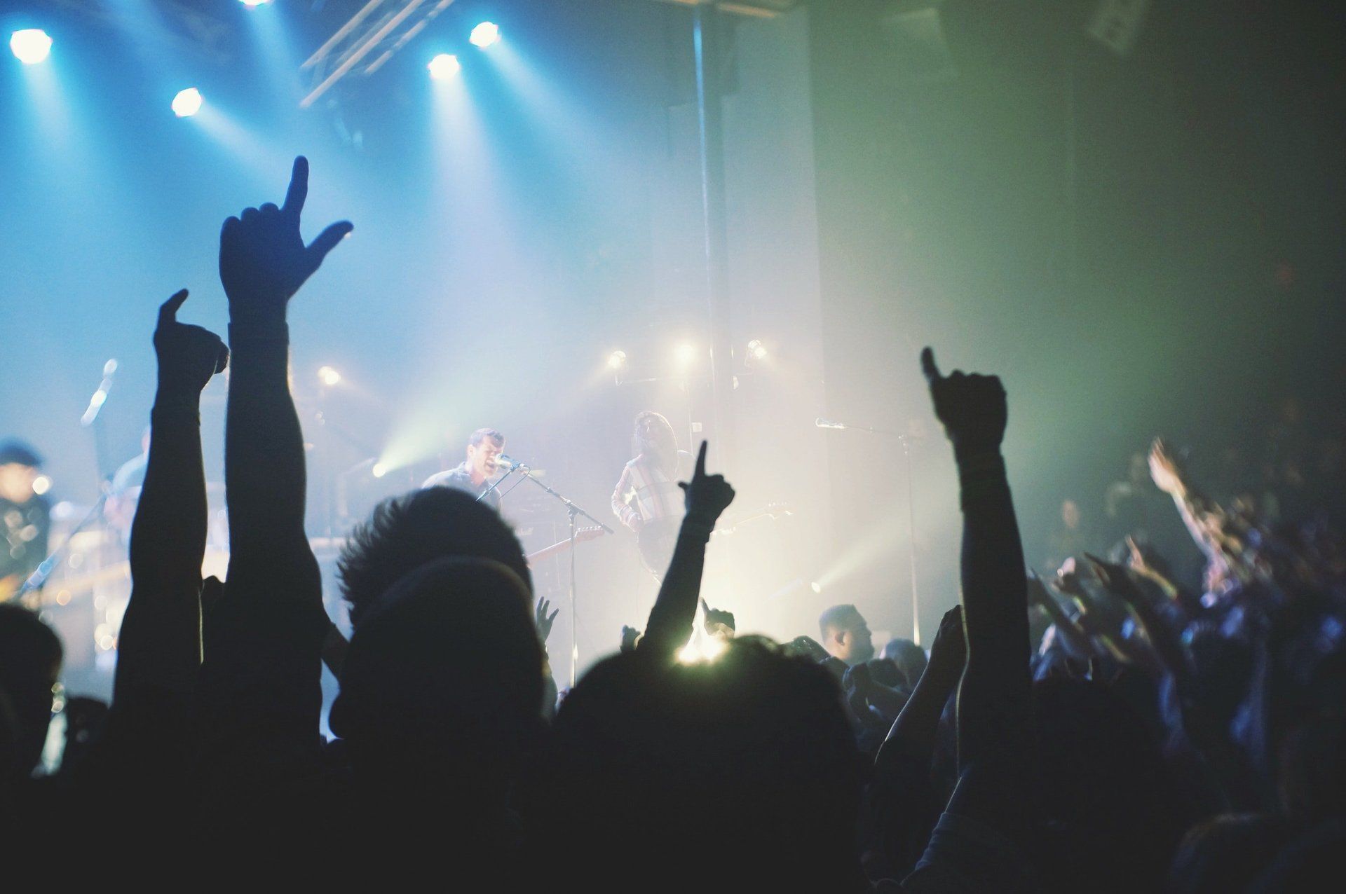 A crowd of people are raising their hands in the air at a concert.