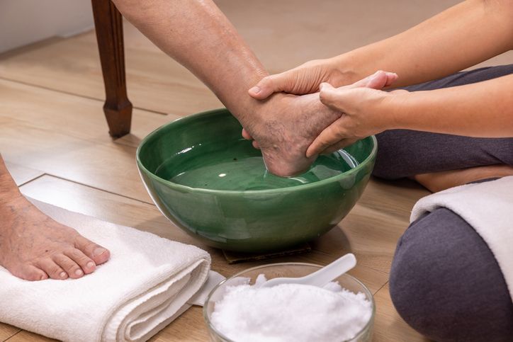 A person is washing another person 's feet in a bowl of water.