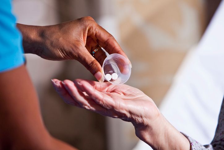 A nurse is pouring pills into a patient 's hand.